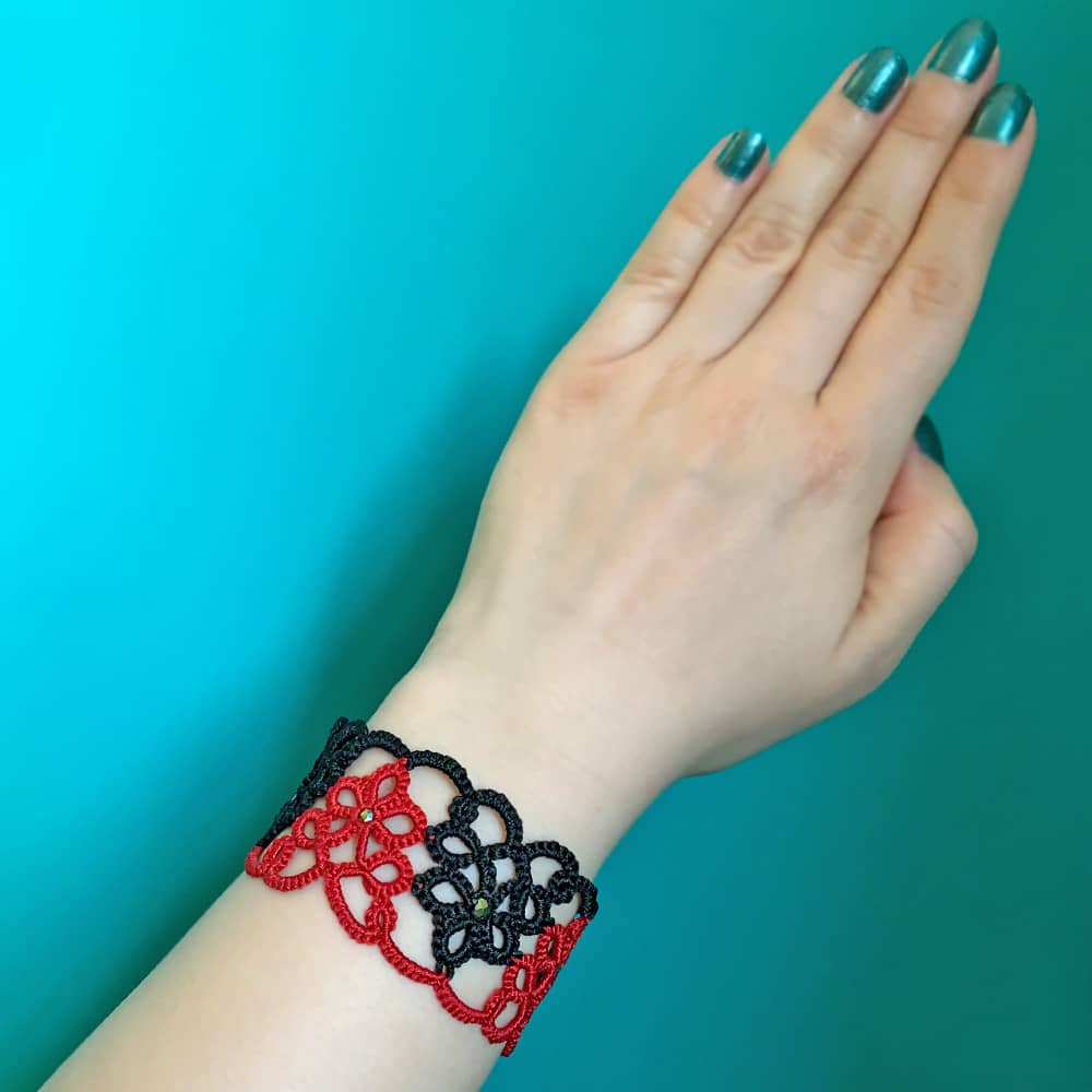 دستبند پهن طرح گل دو رنگ مشکی قرمز روی دست